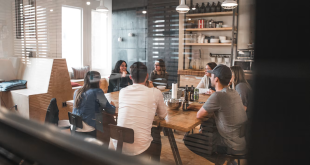 A diverse team of colleagues talking together around a table in a modern office