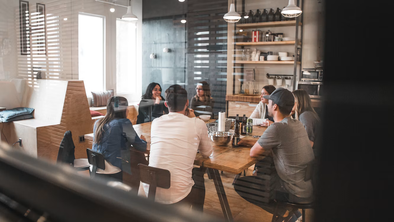 A diverse team of colleagues talking together around a table in a modern office