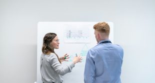 A woman explaining a strategy diagram on a whiteboard to a colleague